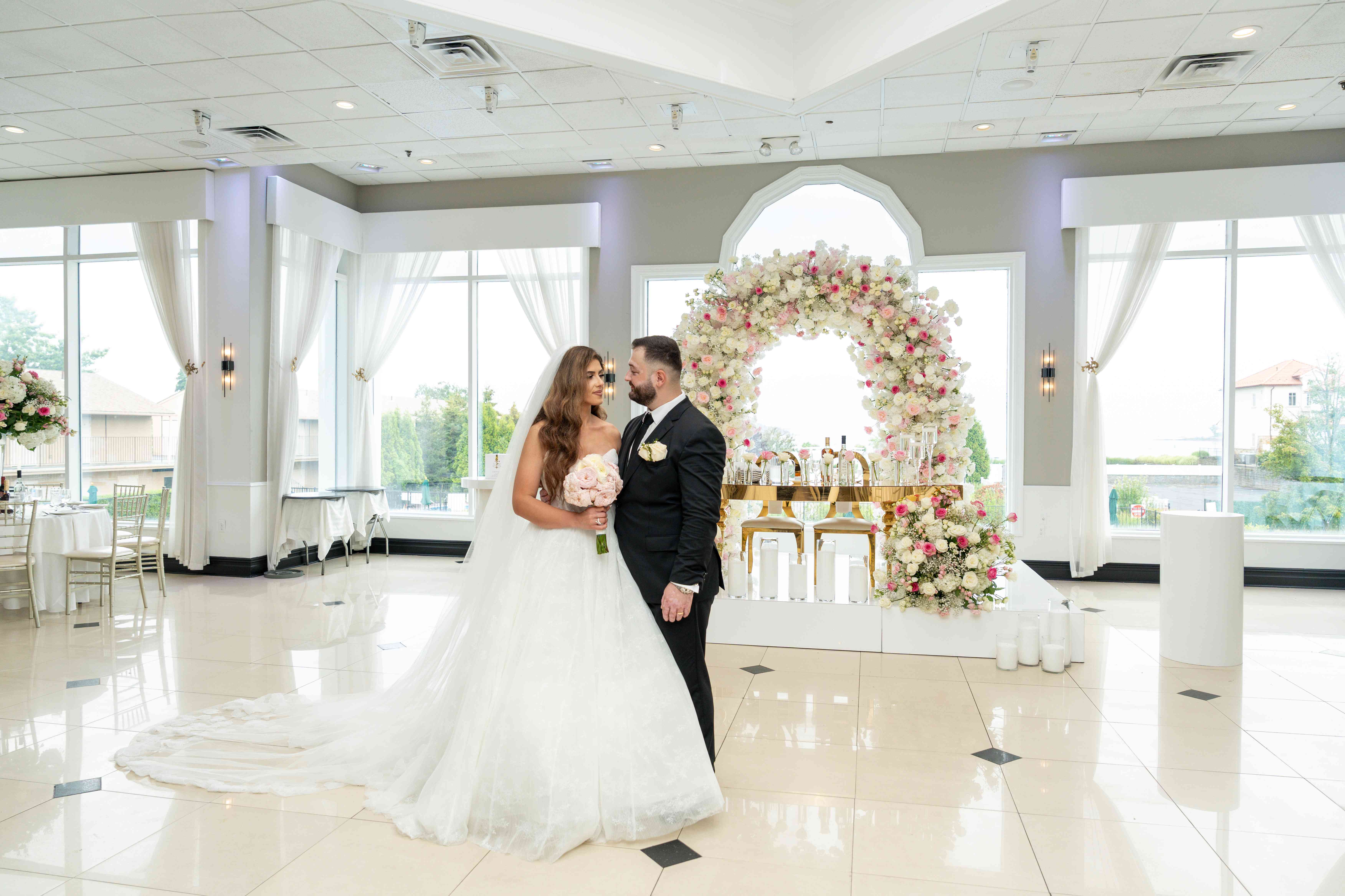 Bride and groom at ceremony with romantic floral arch backdrop