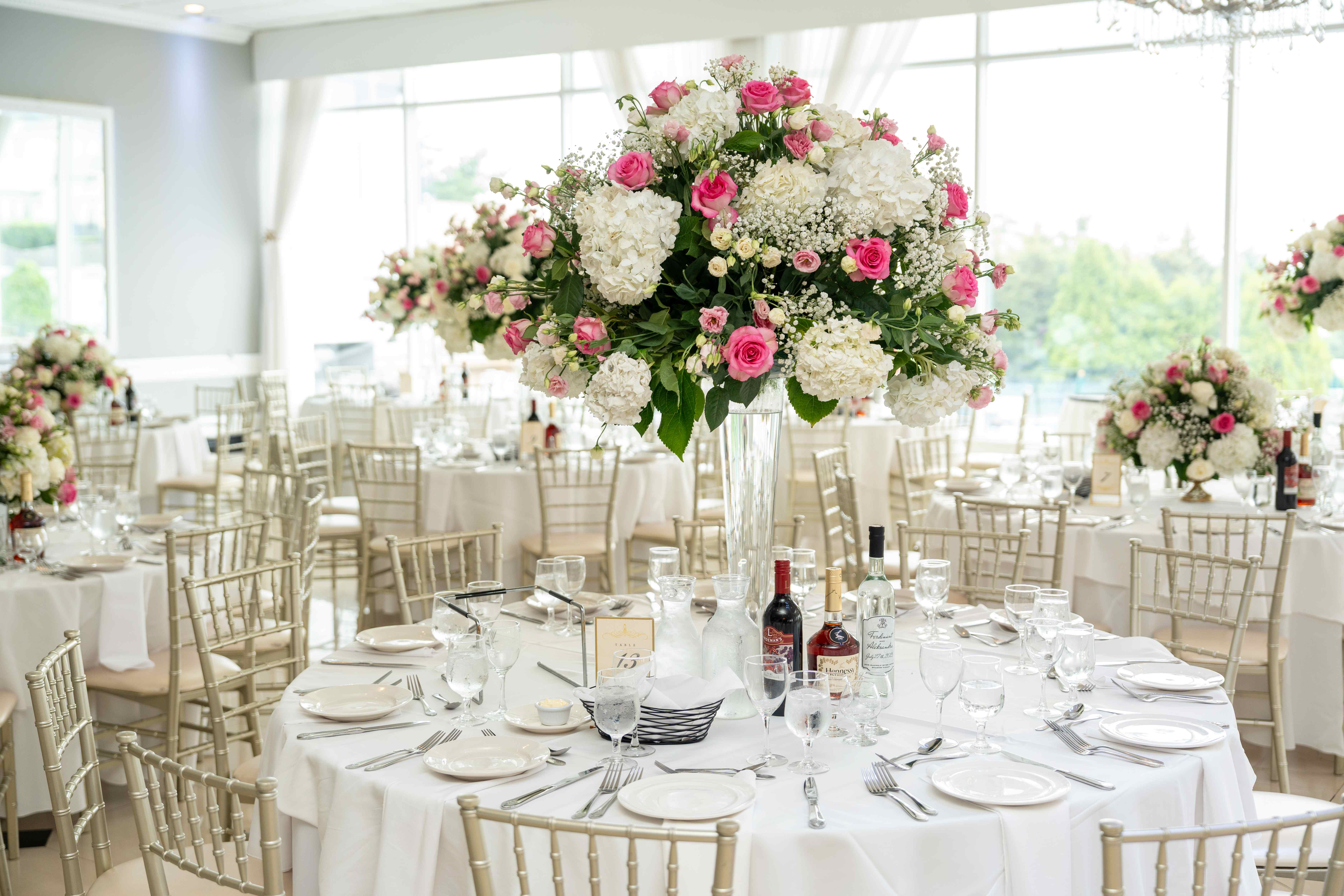 Wedding reception hall with multiple tables featuring tall floral centerpieces