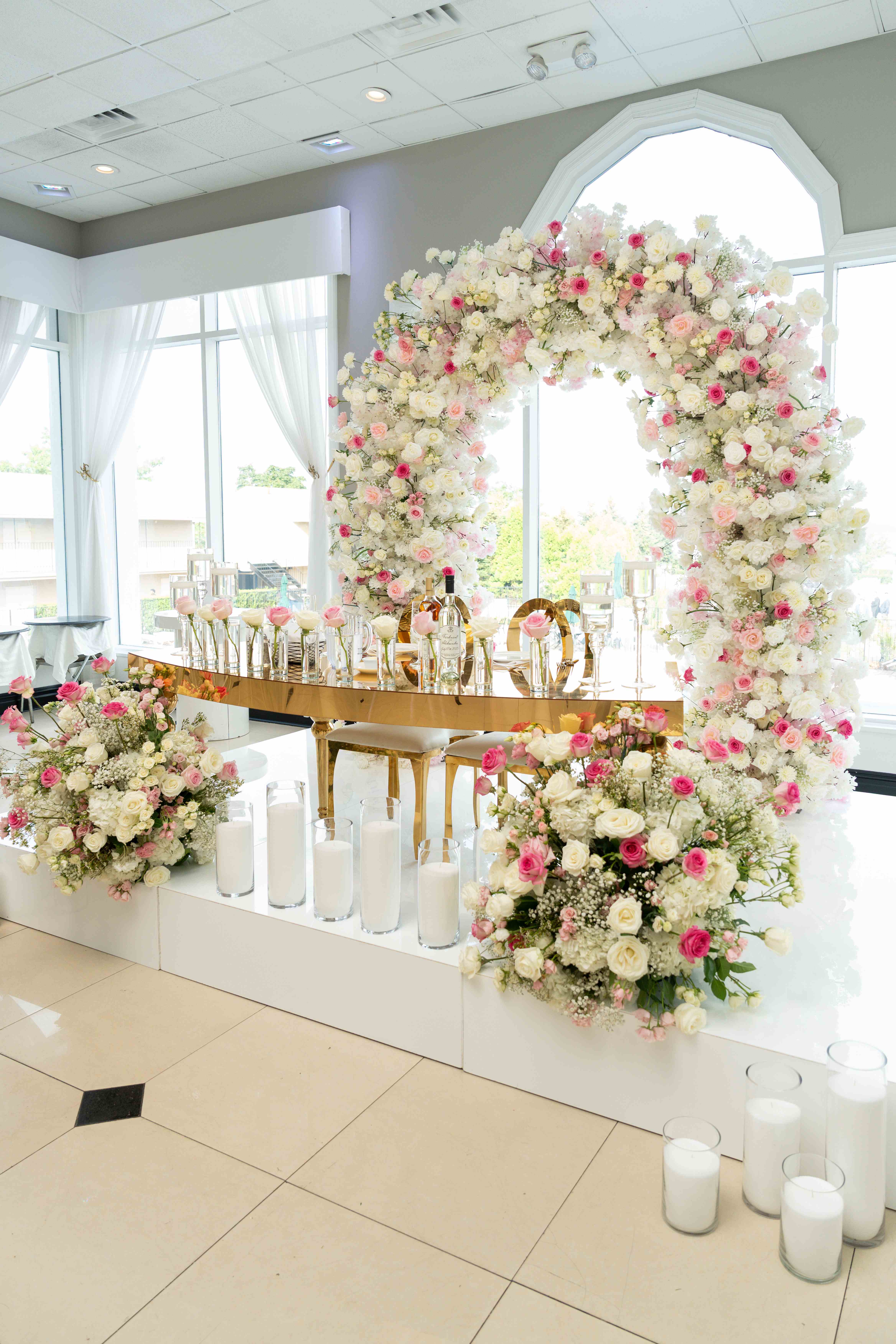 Luxurious wedding sweetheart table with stunning floral arch and gold accents